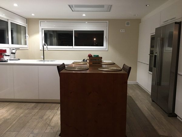 Pavimento y mueble en madera laminada par dar calidez a la cocina de esta reformade casa en Lliçà d'Amunt
